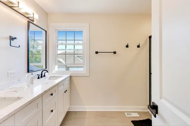 a bathroom with a double vanity sink a mirror and a bathtub