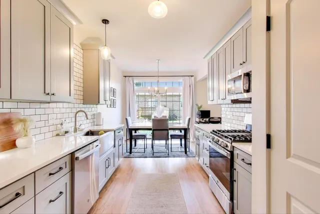 a kitchen with stainless steel appliances kitchen island a table chairs in it and wooden floors