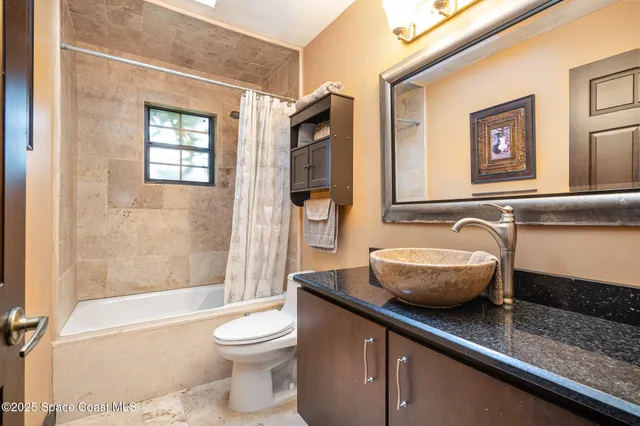 a bathroom with a granite countertop sink a toilet a mirror and shower