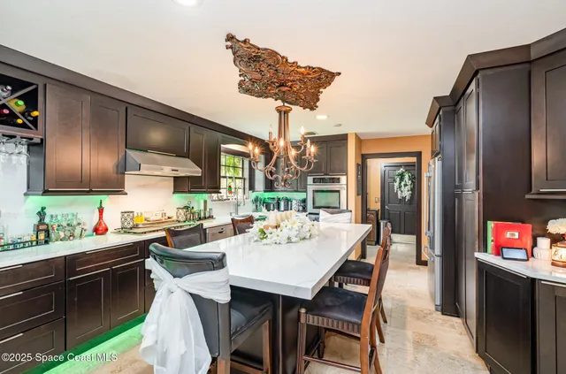 a kitchen with stainless steel appliances kitchen island granite countertop a table chairs in it and wooden floors