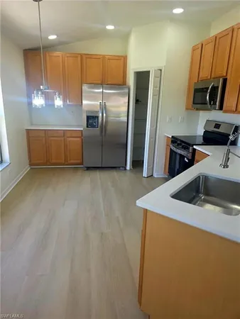 a kitchen with stainless steel appliances granite countertop a sink a stove a refrigerator a washer dryer and a refrigerator