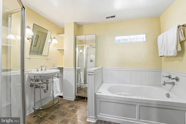 a bathroom with a tub sink shower and mirror