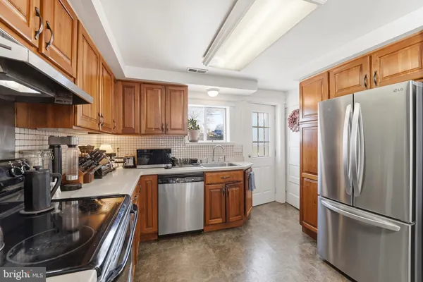 a kitchen with stainless steel appliances granite countertop a refrigerator a sink a stove and a microwave