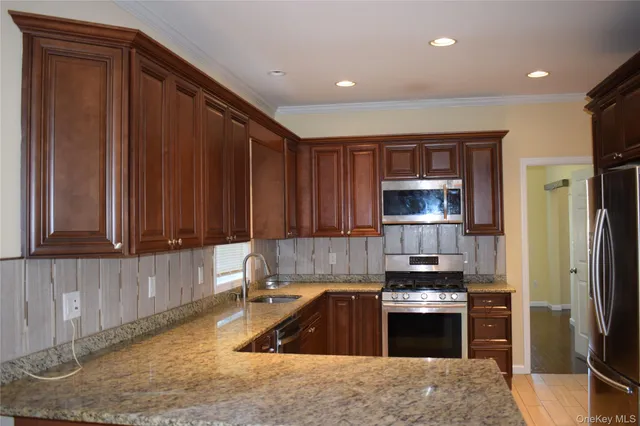 a kitchen with granite countertop wooden cabinets a sink and stainless steel appliances