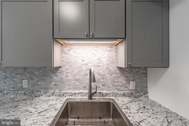a kitchen with granite countertop a sink and a stove top oven