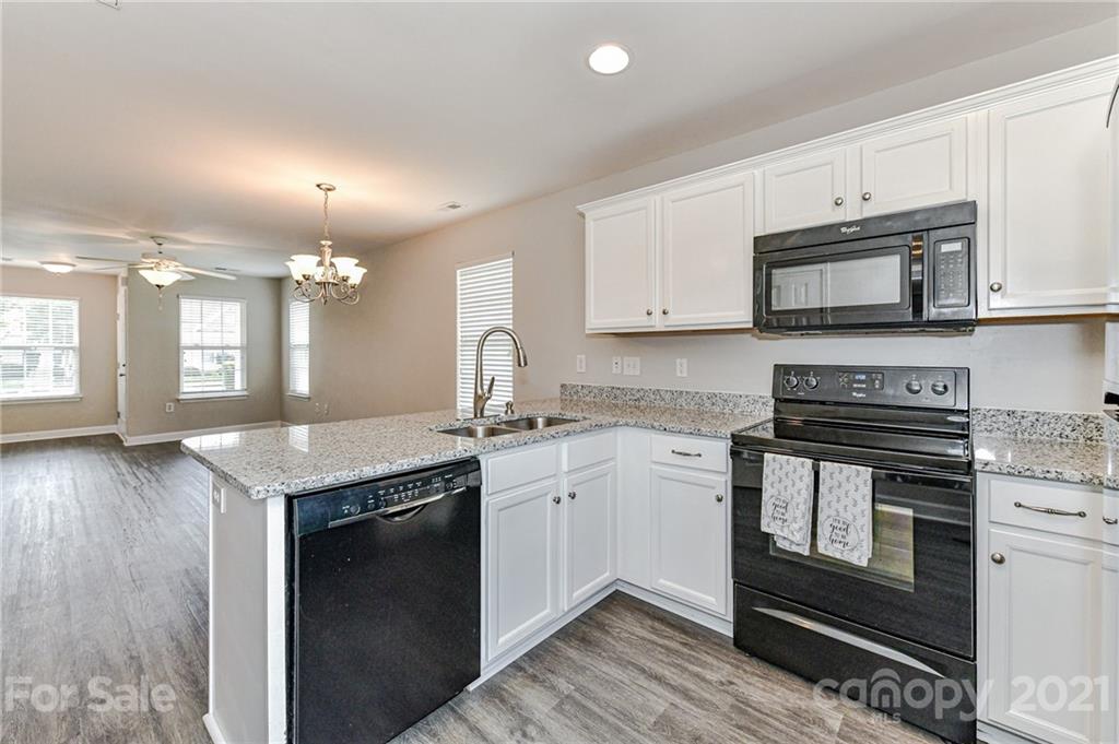 1894 Sandal Brook Road Indian Land, SC 29707 - Photo 13 of 30 a kitchen with granite countertop a stove top oven a sink dishwasher and white cabinets with wooden floor