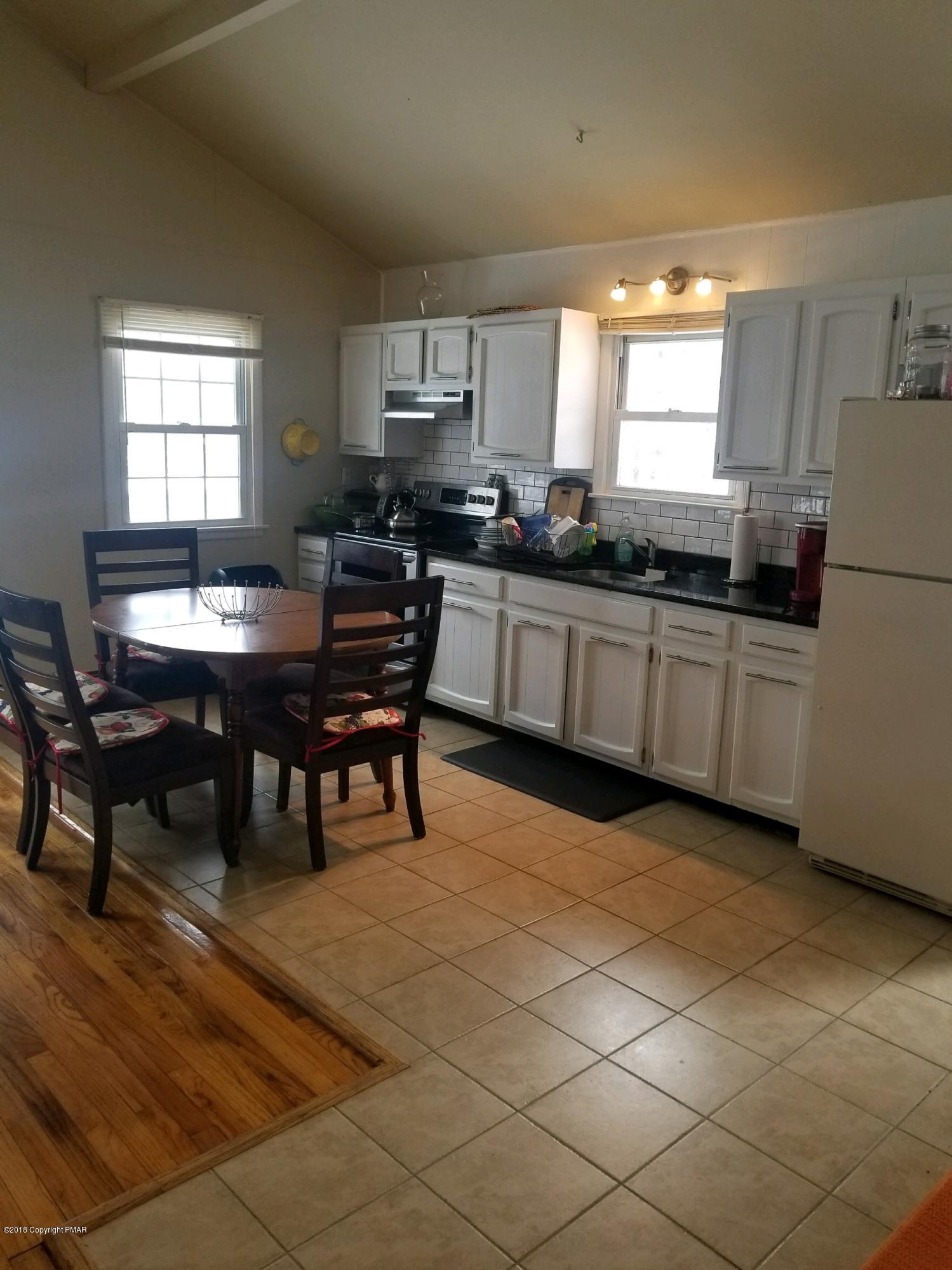 195 Sage Road Long Pond, PA 18334 - Photo 3 of 11 a kitchen with stainless steel appliances granite countertop a sink a stove a dining table and chairs