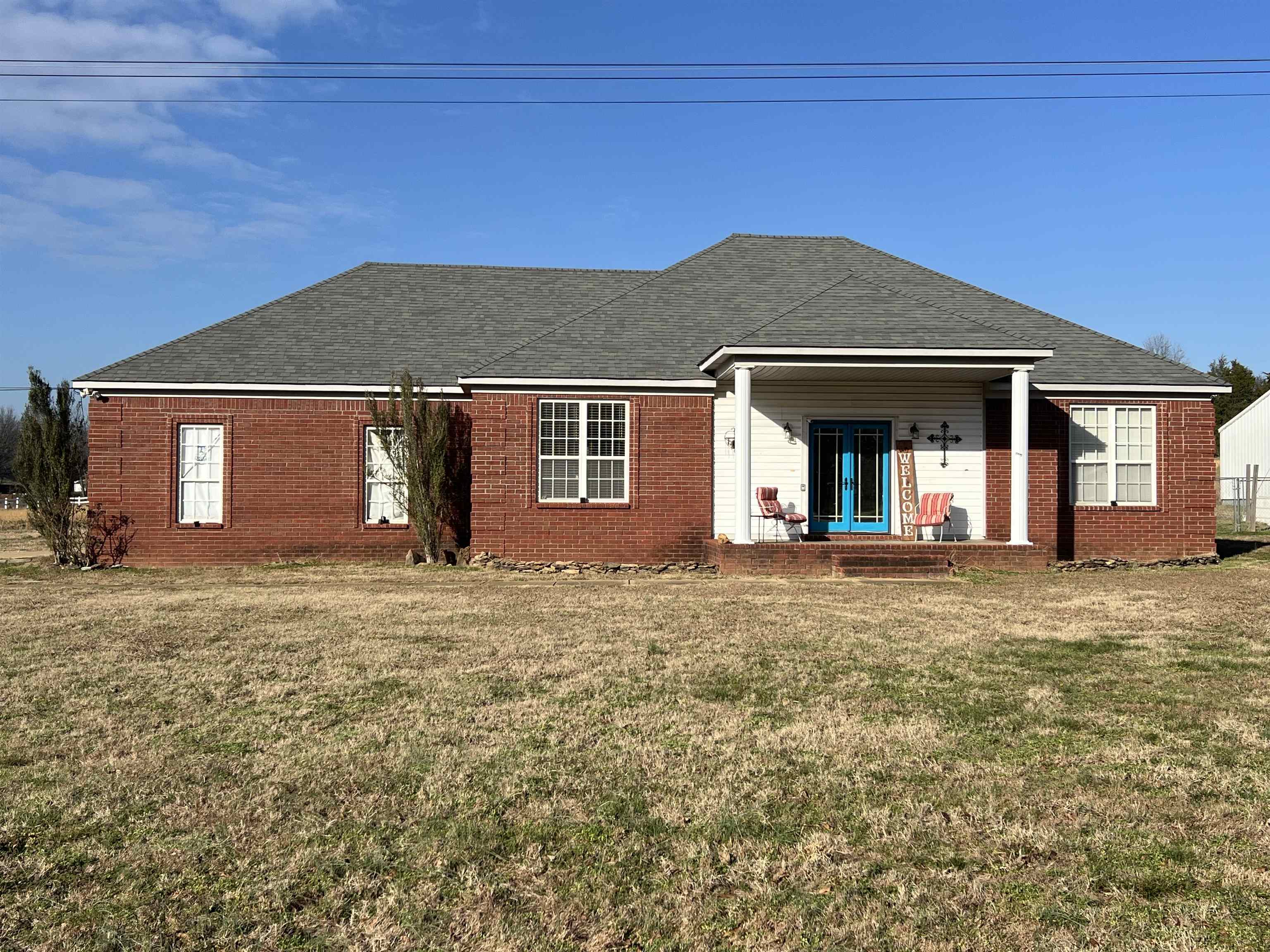 Front of property featuring a lawn, french doors, brick siding, and a shingled roof