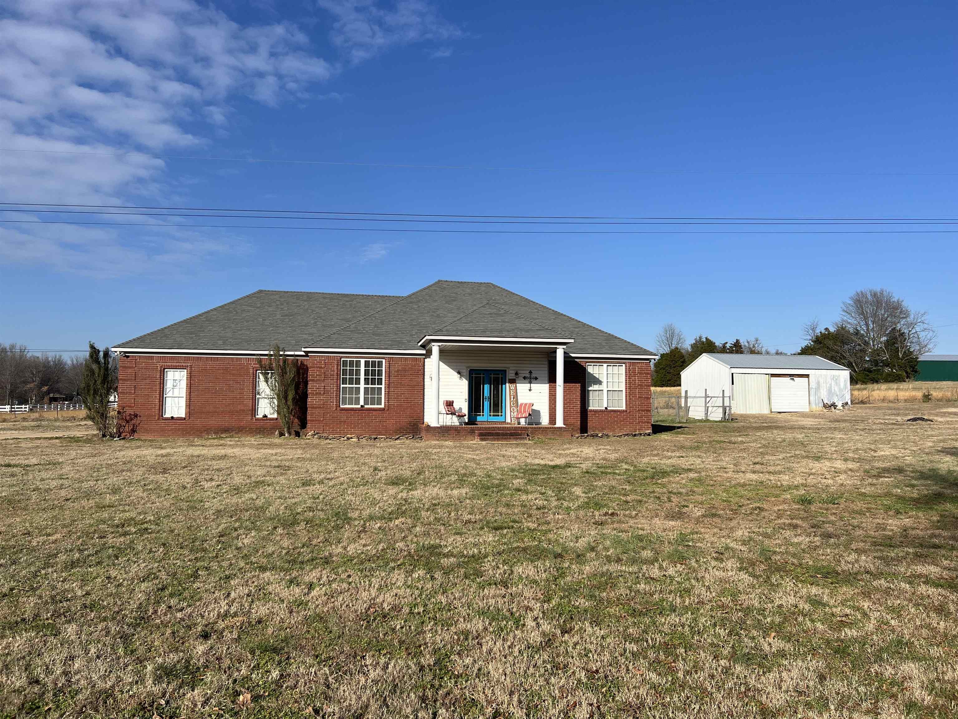 1990 Gainsville Road Mason, TN 38049 - Photo 2 of 13 Front view of house featuring a lawn, an outbuilding, brick siding, and roof with shingles