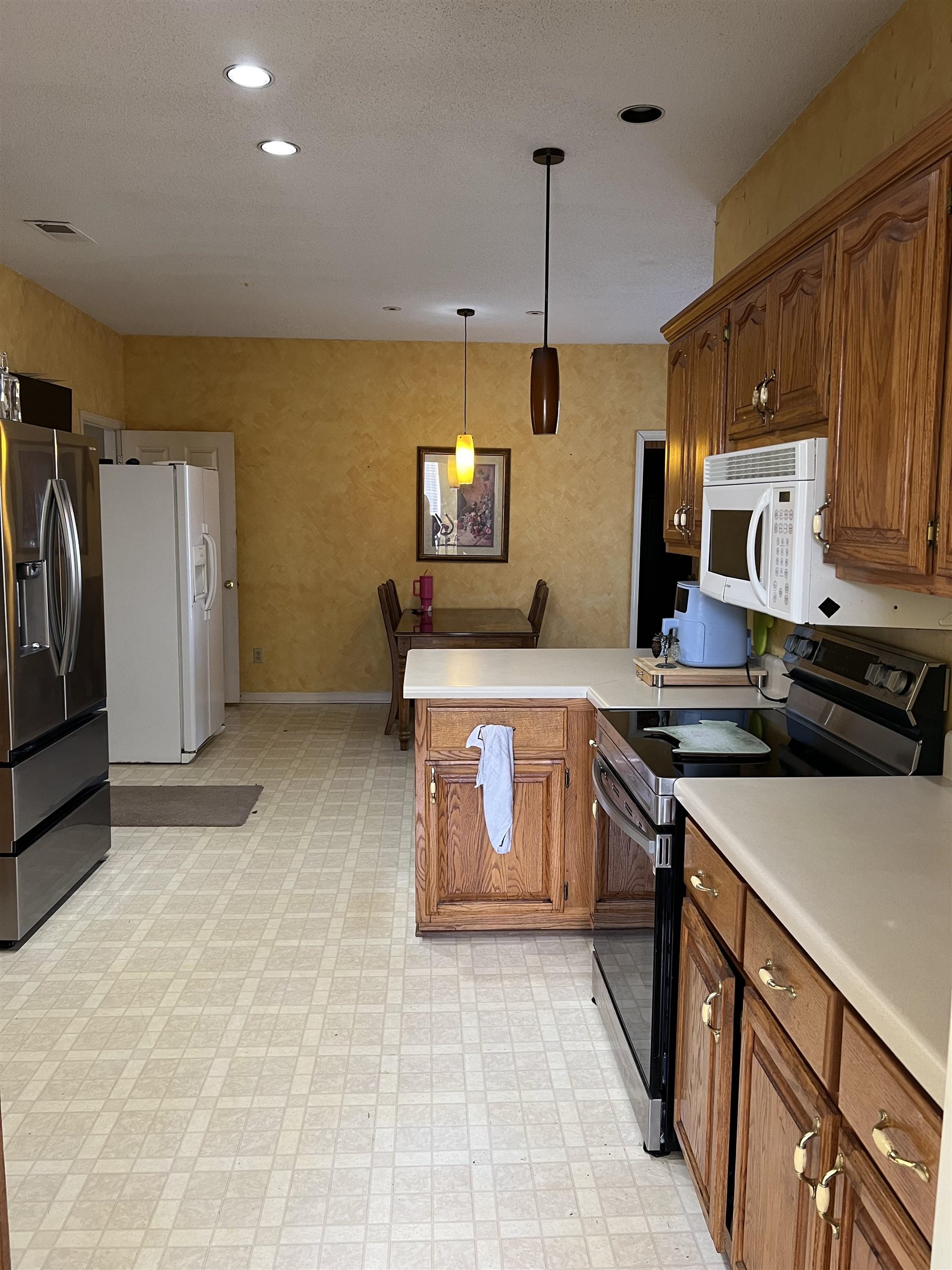 1990 Gainsville Road Mason, TN 38049 - Photo 9 of 13 Kitchen with range with electric stovetop, brown cabinetry, stainless steel fridge, light countertops, and a peninsula