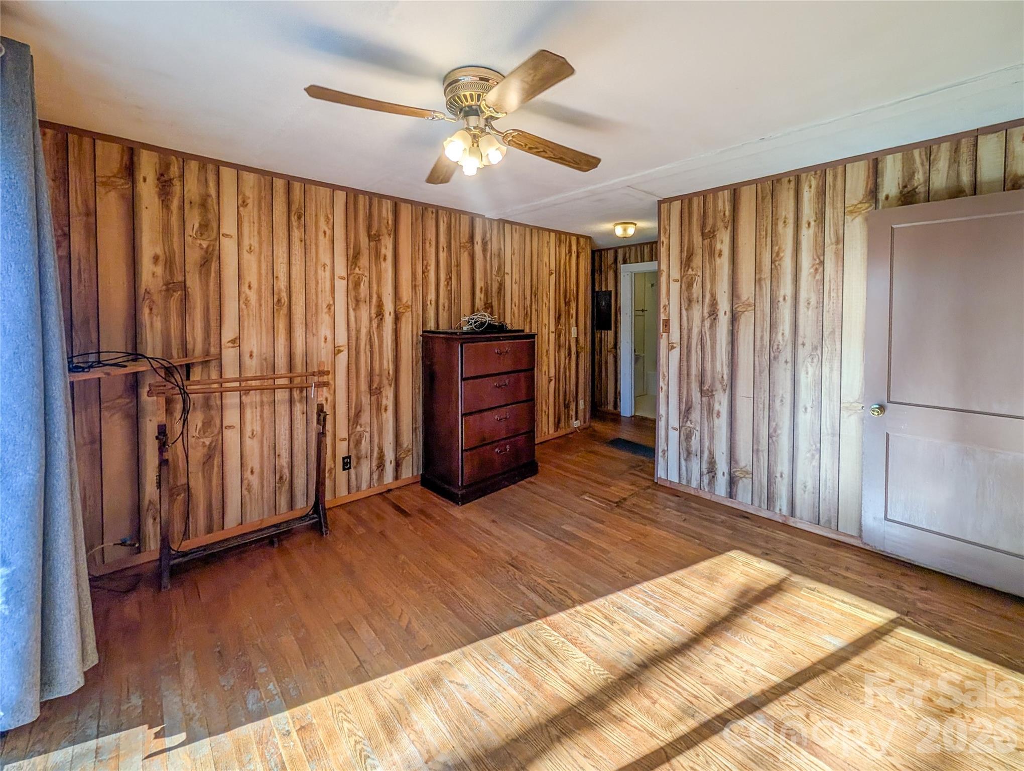 97 Tom Sparks Road Spruce Pine, NC 28777 - Photo 14 of 35 a view of a bedroom with wooden floor staircase and a ceiling fan