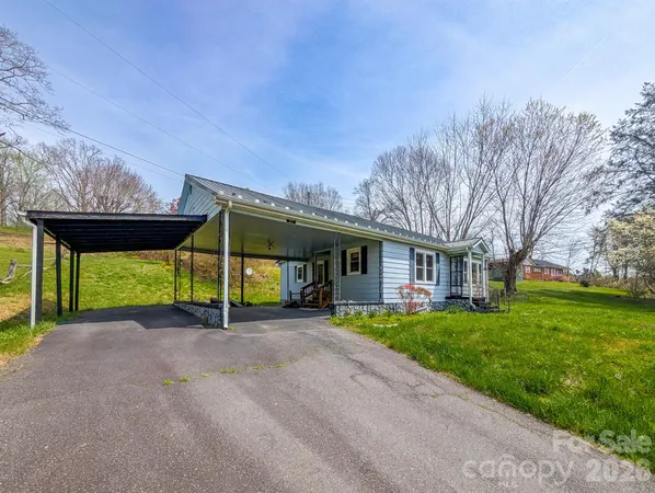 a view of a house with a yard and table and chairs under an umbrella