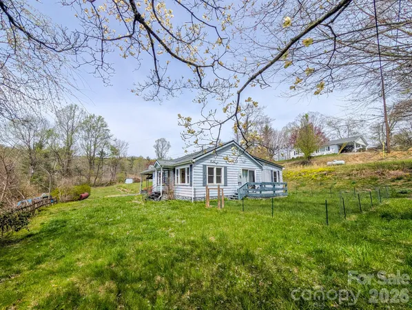 a view of a house with a big yard and large trees