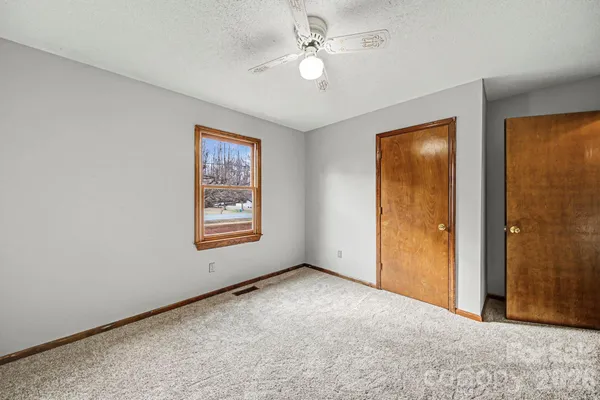 an empty room with windows and fan