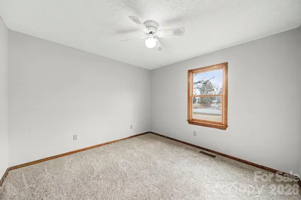 an empty room with windows and fan