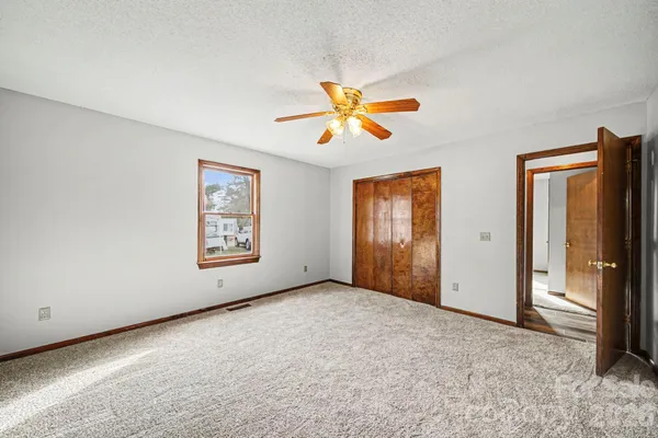 an empty room with windows and fan