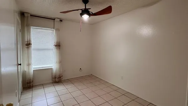 an empty room with windows and fan