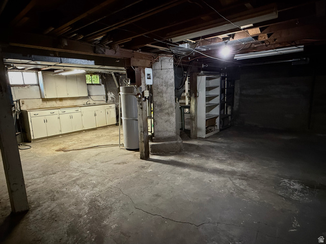 151 South Roosevelt Helper, UT 84526 - Photo 13 of 20 Basement utility space featuring a concrete floor, exposed ceiling joists, and a built-in cabinetry run with a sink