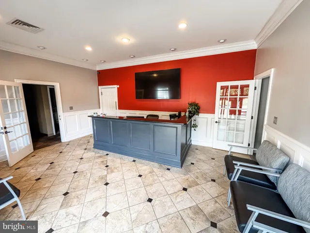a living room with stainless steel appliances furniture a flat screen tv and a refrigerator