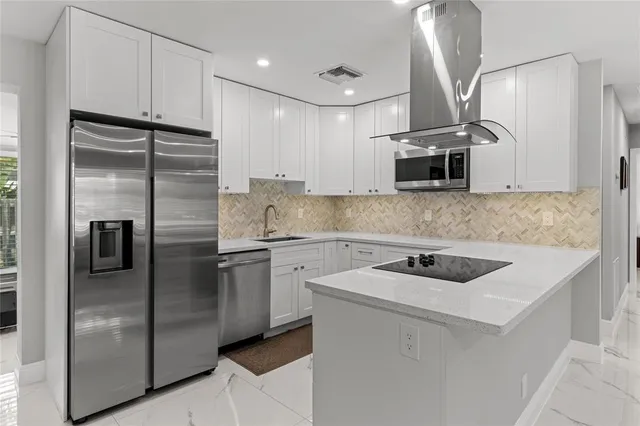 a kitchen with kitchen island a dining table chairs and refrigerator