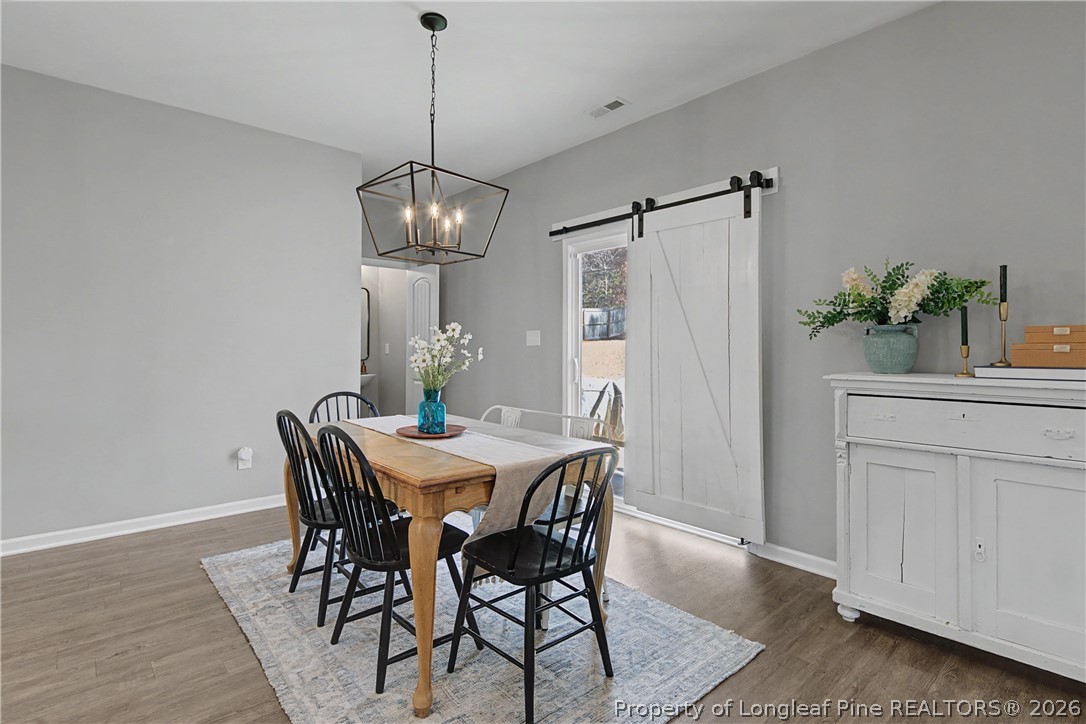 143 Ledgebrook Lane Raeford, NC 28376 - Photo 14 of 50 a dining room with wooden floor a chandelier a wooden table and chairs