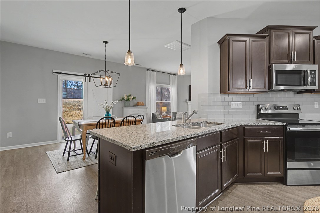 143 Ledgebrook Lane Raeford, NC 28376 - Photo 17 of 50 a kitchen with kitchen island granite countertop a sink a counter space appliances and cabinets