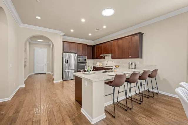 a kitchen with stainless steel appliances granite countertop a refrigerator a stove top oven a sink dishwasher and a dining table with wooden floor
