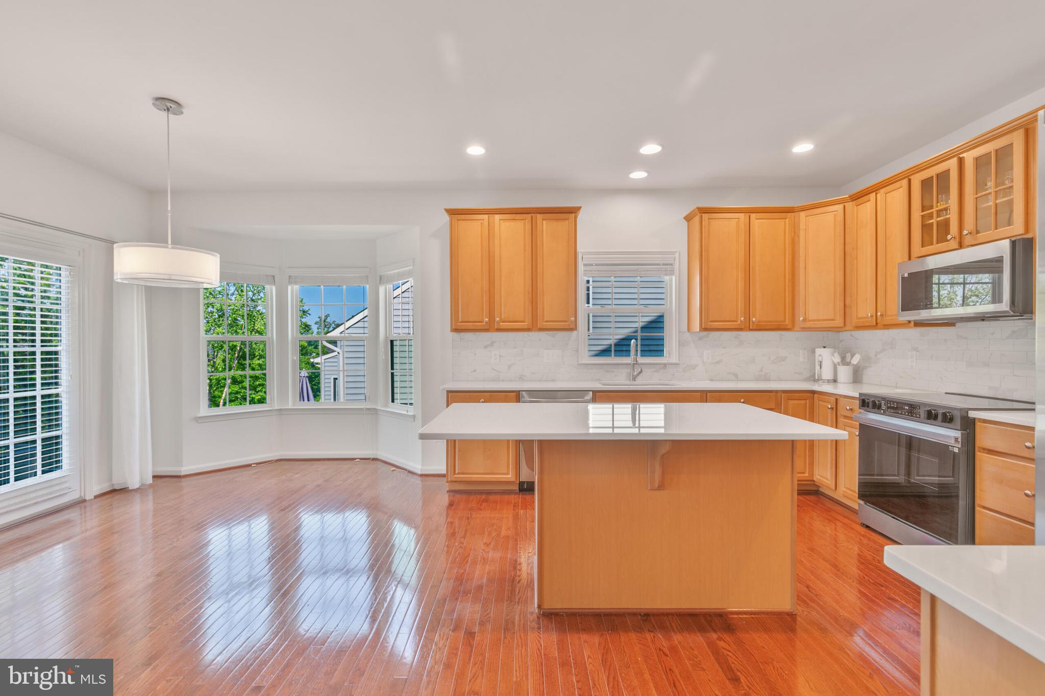 40652 Banshee Drive Leesburg, VA 20175 - Photo 16 of 51 a kitchen with stainless steel appliances granite countertop a sink a stove a refrigerator a microwave oven with wooden floor and cabinets