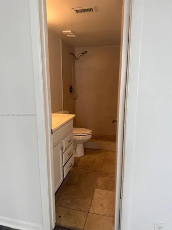 a bathroom with a granite countertop toilet a sink and a mirror