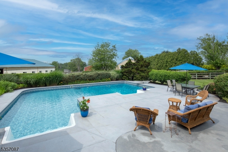 338 Rileyville Road Ringoes, NJ 08551 - Photo 16 of 33 a view of a swimming pool with a table and chairs under an umbrella