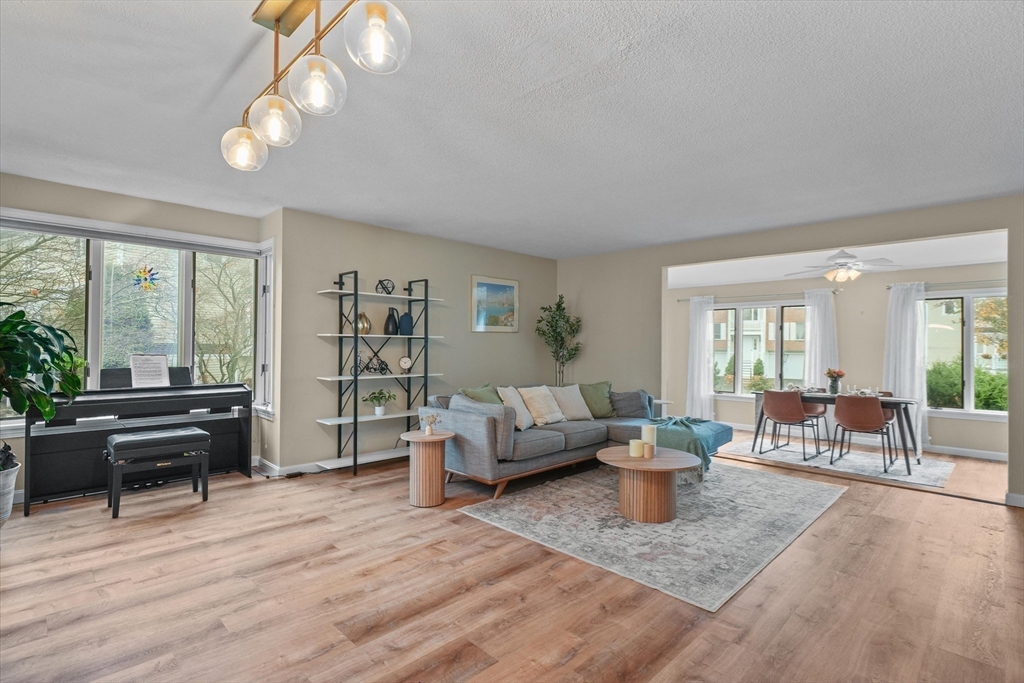 37 Constitution Lane, Unit 12 Danvers, MA 01923 - Photo 11 of 38 a living room with furniture a large window and a chandelier