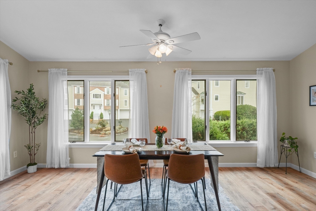 37 Constitution Lane, Unit 12 Danvers, MA 01923 - Photo 14 of 38 a dining room with wooden floor a chandelier fan a potted plant and windows