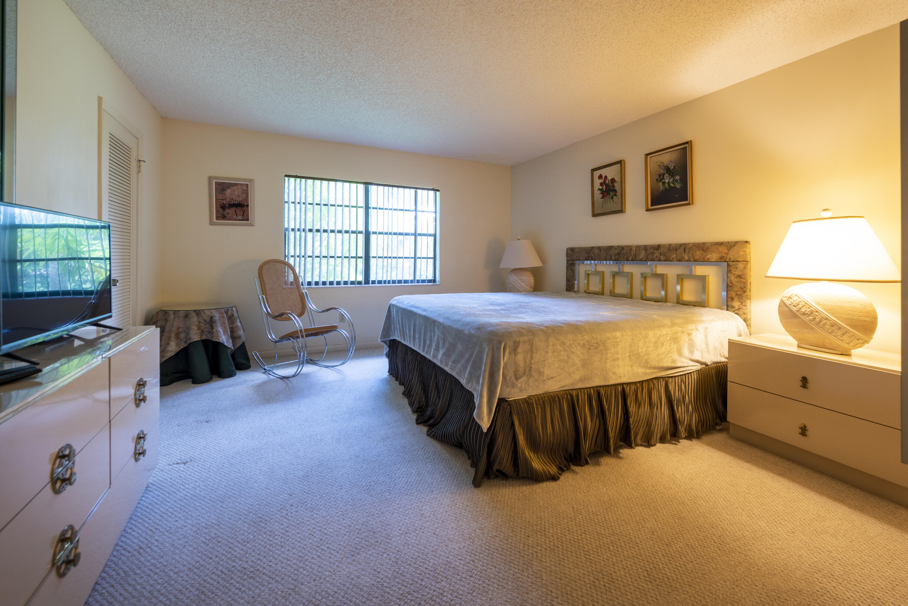 9199 Pecky Cypress Lane, Unit 7F Boca Raton, FL 33428 - Photo 13 of 20 a spacious bedroom with a bed and a dresser next to a window