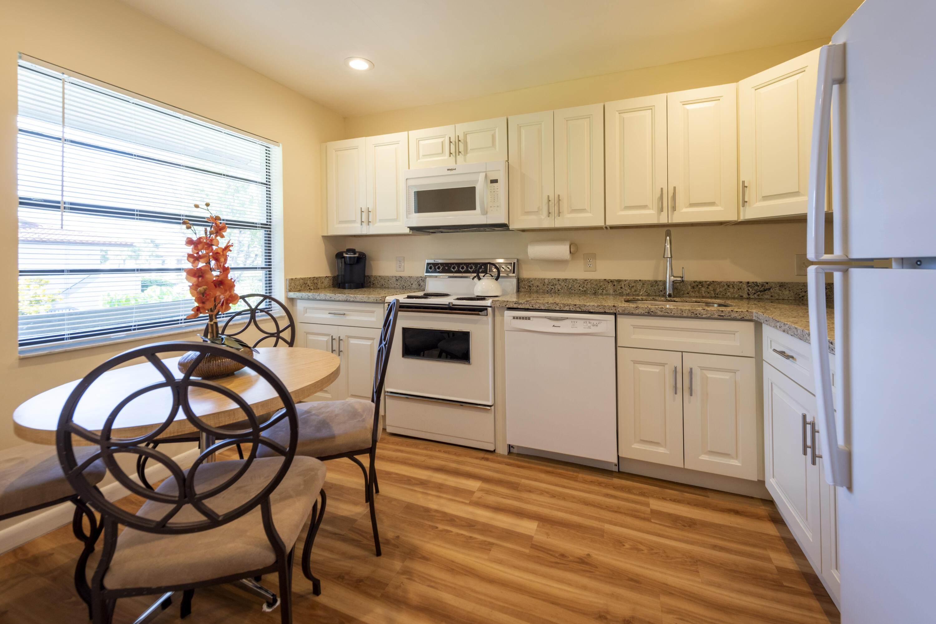 9199 Pecky Cypress Lane, Unit 7F Boca Raton, FL 33428 - Photo 4 of 20 a kitchen with stainless steel appliances granite countertop a stove top oven a sink dishwasher and white cabinets with wooden floor