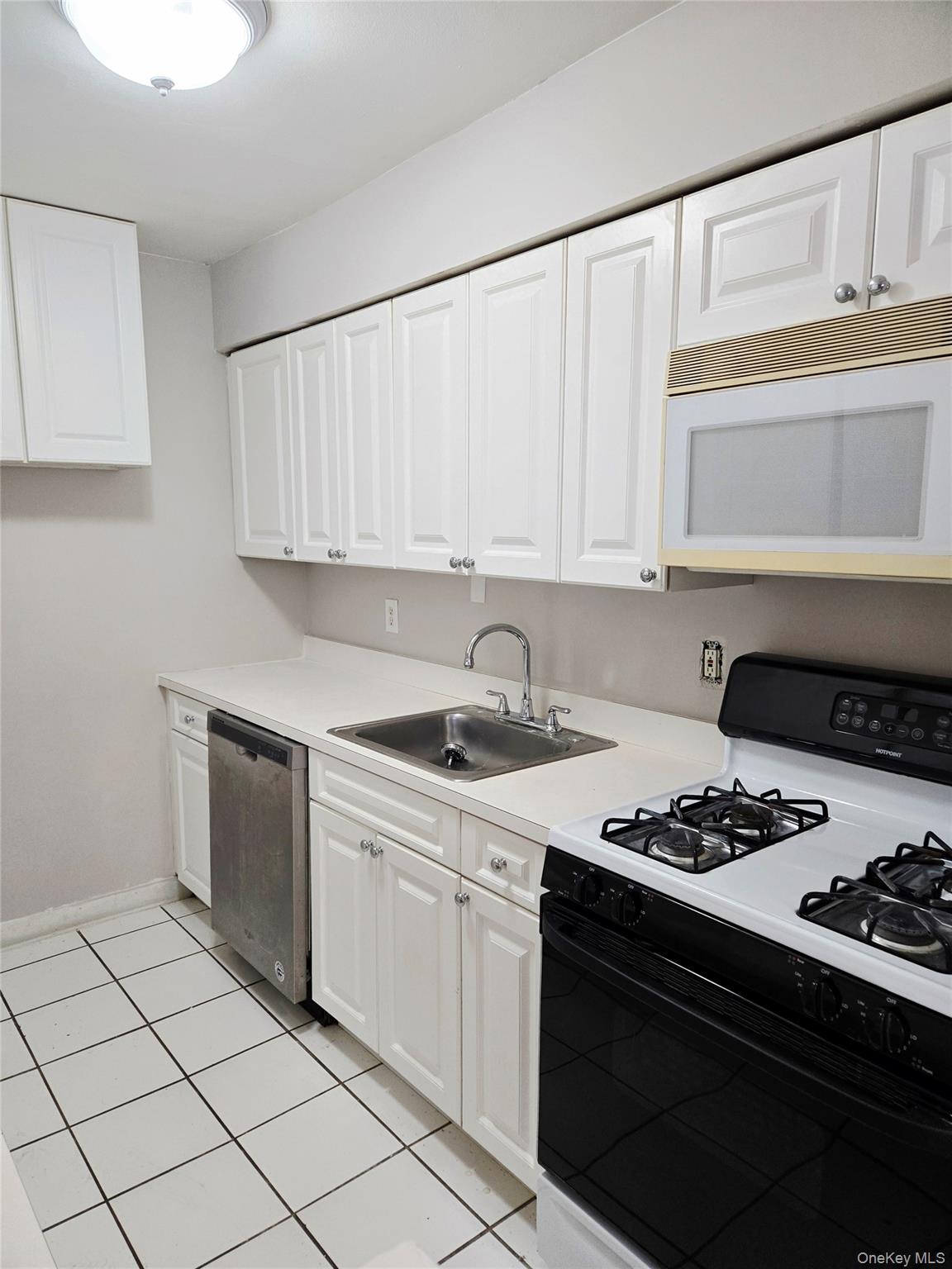79 Pointe Circle South, Unit 79 Coram, NY 11727 - Photo 8 of 39 Kitchen with gas range oven, light countertops, white microwave, white cabinetry, and stainless steel dishwasher