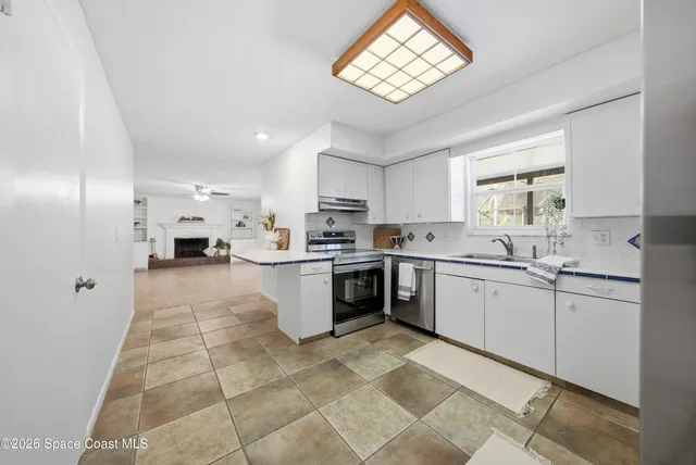 a kitchen with stainless steel appliances granite countertop a sink a stove a refrigerator cabinets and a window