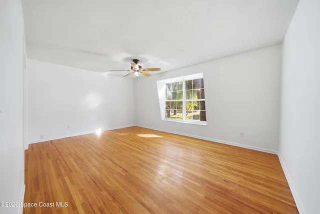 a view of empty room with wooden floor and fan