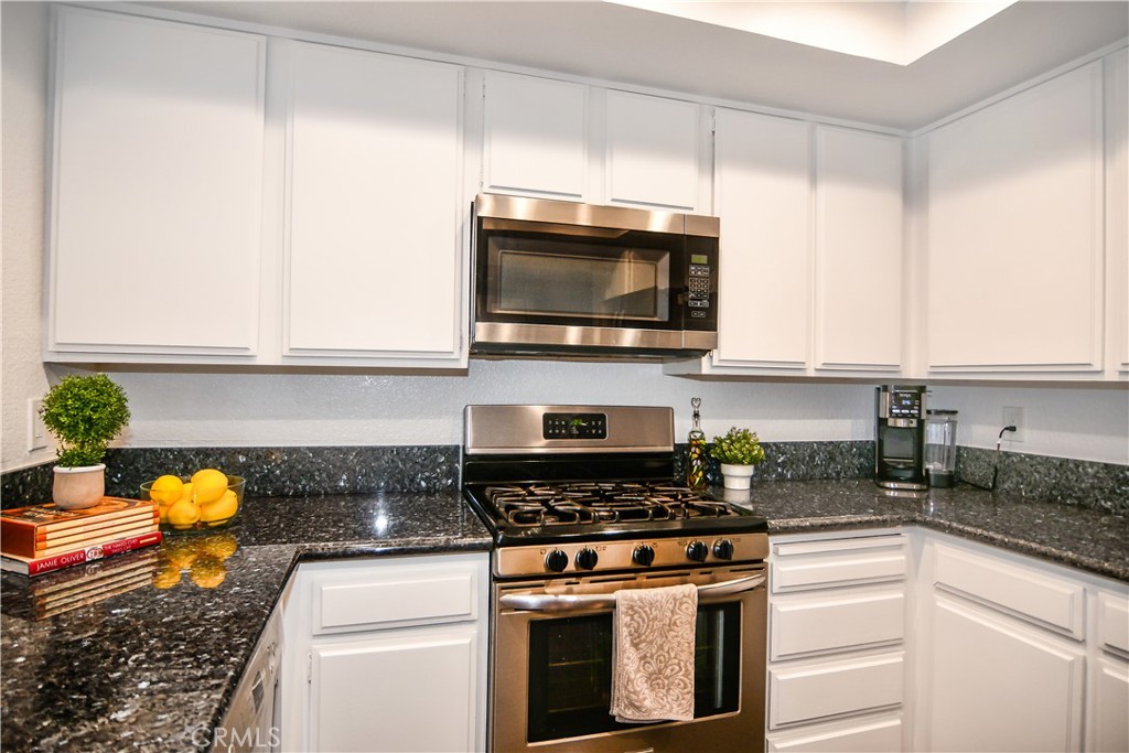 16551 Grunion Lane, Unit 204 Huntington Beach, CA 92649 - Photo 11 of 45 a kitchen with stainless steel appliances granite countertop a stove a microwave and cabinets