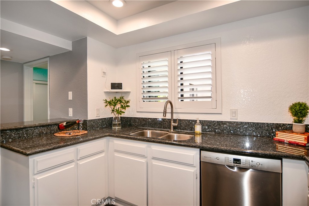 16551 Grunion Lane, Unit 204 Huntington Beach, CA 92649 - Photo 12 of 45 a kitchen with granite countertop a sink and a white cabinets