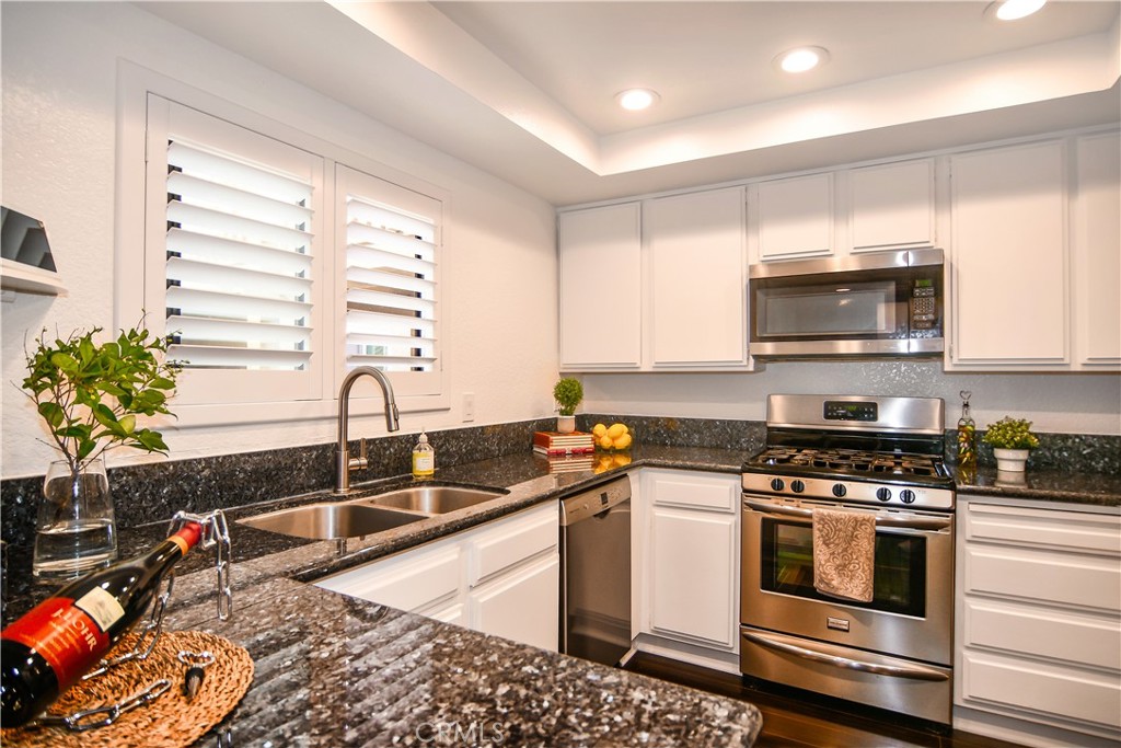 16551 Grunion Lane, Unit 204 Huntington Beach, CA 92649 - Photo 5 of 45 a kitchen with granite countertop a stove a sink and a microwave