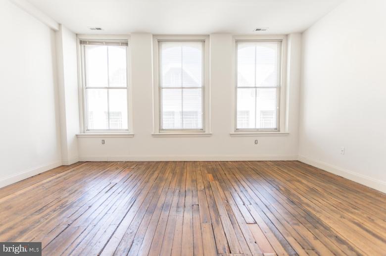 1222-26 Arch Street, Unit 507 Philadelphia, PA 19107 - Photo 1 of 22 an empty room with wooden floor and windows