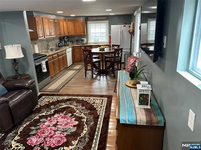 a kitchen with stainless steel appliances granite countertop a stove top oven a dining table and chairs with wooden floor