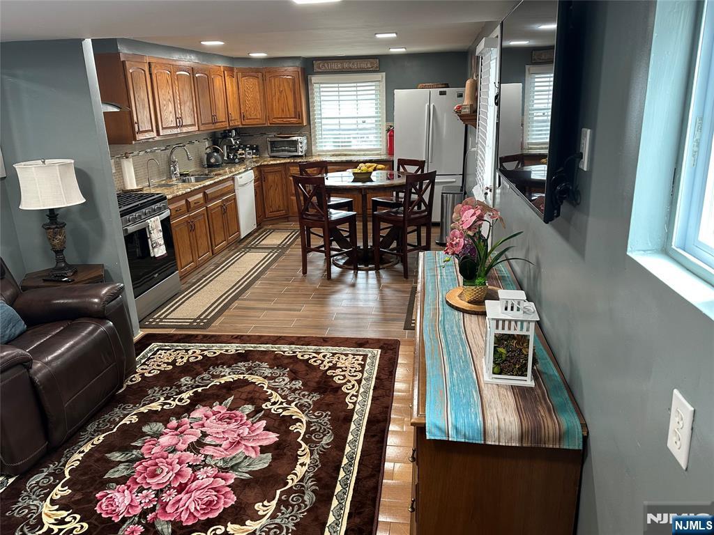 15 2nd Street Lodi, NJ 07644 - Photo 8 of 32 a kitchen with stainless steel appliances granite countertop a stove top oven a dining table and chairs with wooden floor