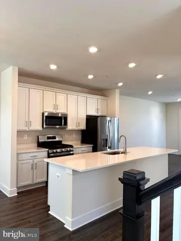 a kitchen with a sink a stove a refrigerator a kitchen island and chairs