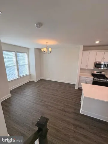 a view of an empty room with wooden floor and stairs