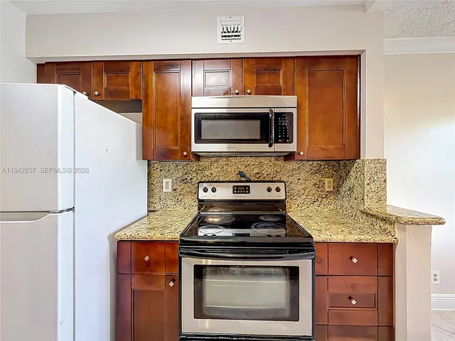 a kitchen with granite countertop a sink stove and cabinets