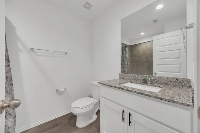 a bathroom with a granite countertop sink a toilet and a mirror