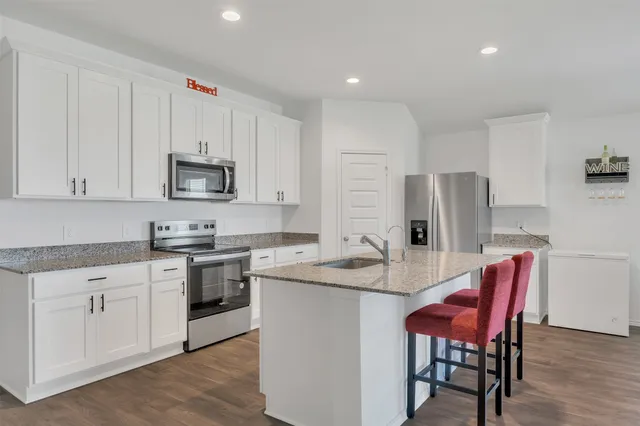 a kitchen with stainless steel appliances granite countertop a table chairs sink refrigerator and cabinets