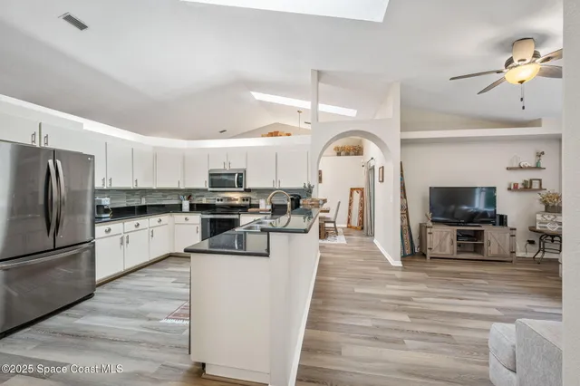 a large kitchen with cabinets a counter top space stainless steel appliances and wooden floor