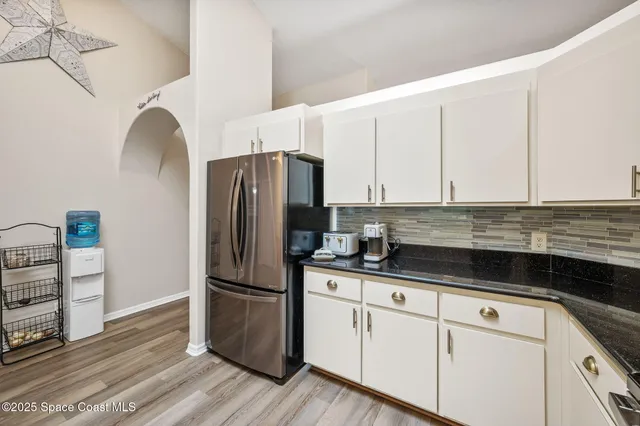 a kitchen with granite countertop a refrigerator and cabinets